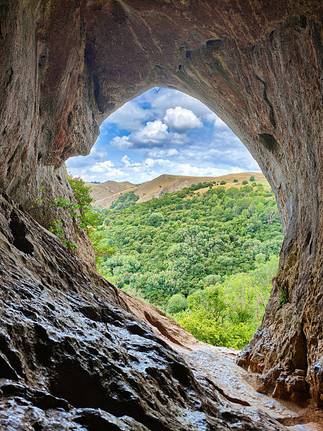 A woman doing yoga from a cave with a beautiful view.