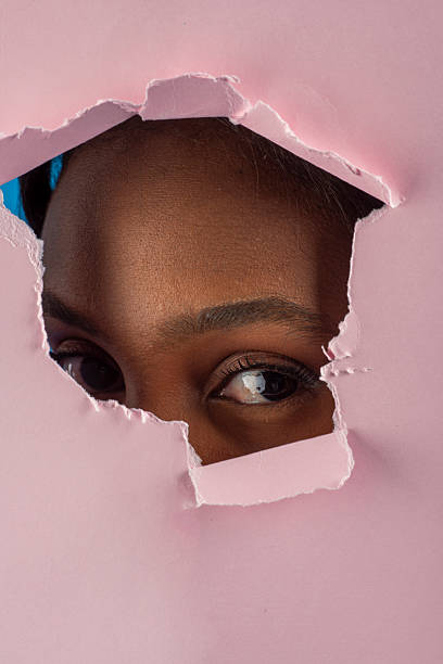 istock Curious model gazing through torn pink paper 2226945613
