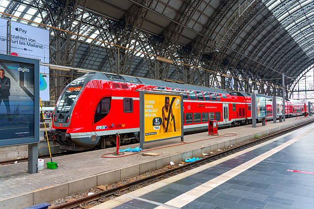 Frankfurt, Germany - June 10, 2025: Regional train in bright red color parked on the platform of Frankfurt Main Station, showcasing modern architecture and bustling station atmosphere.