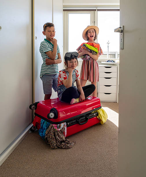 Real moments of family packing their suitcases and bags in their homes to prepare for an upcoming trip. Children happy and ready for vacation.