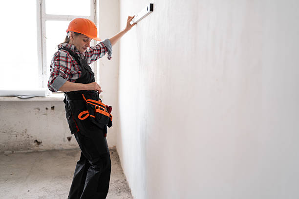 istock Female construction worker or builder wearing protective helmet uses spirit level for measurement wall during renovation or construction work 2226951437