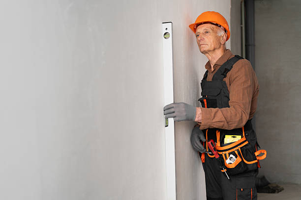 istock Elderly man builder in hardhat measuring wall with spirit level tool 2226951748