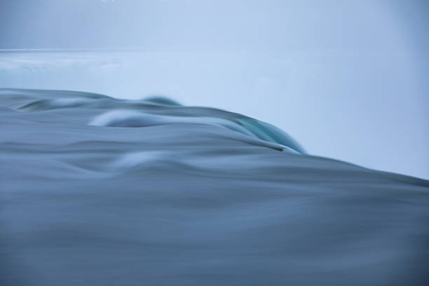 Niagara Falls, Horseshoe Falls, from the American side, Canada on the other side of the falls, mist rising, bright sunshine, close up, long exposure to smooth the water's flow.