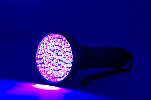 istock A powerful ultraviolet flashlight with numerous small led bulbs casting a vibrant purple glow on a dark blue surface. 2226953143