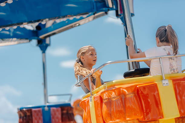istock Two girls having fun on a spinning carousel ride at amusement park 2226954576