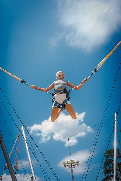 istock Girl jumping high on bungee trampoline under blue sky 2226954577