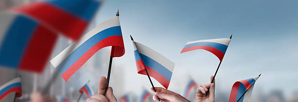 istock Russia flags in their hands on a blurred urban background 2226954912