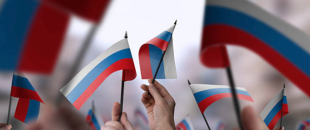 istock Russia flags in their hands on a blurred urban background 2226954960