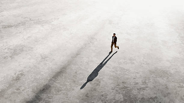 istock Top view of businessman running fast casting a long shadow on a gray surface 2226956408