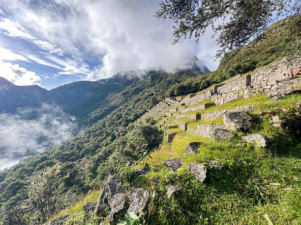 Stone terraces built on a lush green mountain slope with mist-covered peaks. Historic agricultural terraces in a mountainous landscape. Scenic outdoor nature and heritage site.