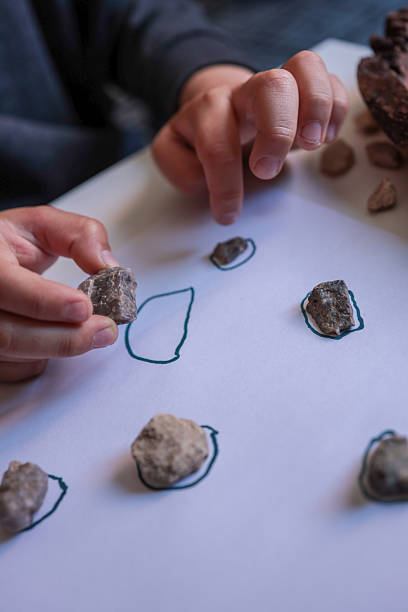 istock Child sorting small natural stones onto drawn circles on white paper. Educational and sensory activity promoting fine motor skills, focus, and nature-based learning at home 2226963332