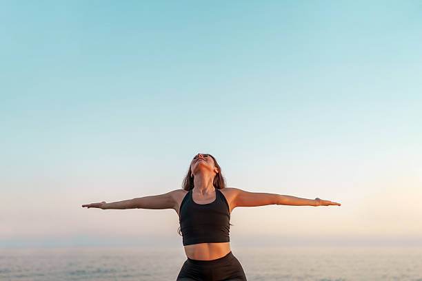 istock Woman practicing yoga warrior two pose on the beach at sunset 2226965104