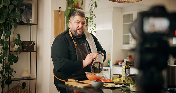 istock Ingredients, cooking and man with live streaming in kitchen for dinner recipe, meal prep or video recording. Culinary influencer, content creation or person with cuisine tutorial or nutrition in home 2226965470