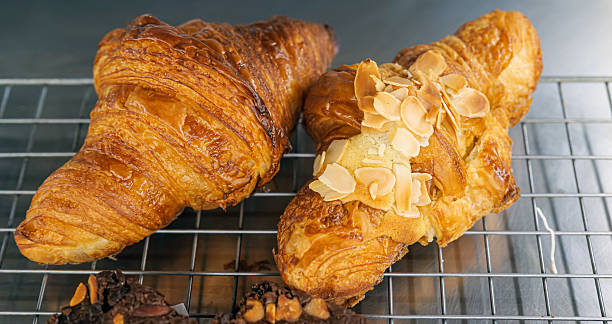 Freshly baked homemade croissants on a grid in the bakery.
