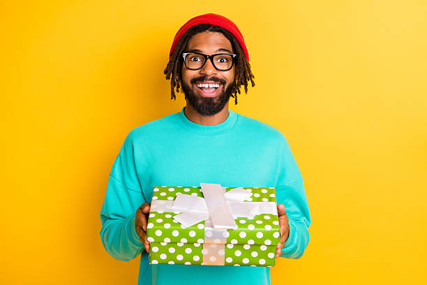 istock Portrait of brunette impressed guy hold present wear cap spectacles blue pullover isolated on yellow vivid color background 2226970345