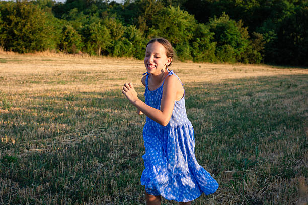 Happy girl is running on a meadow during a summer day in the countryside