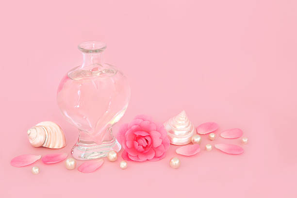 Rose flower perfume feminine gift in heart shape bottle on pink. Fragrance for Valentines, birthday, anniversary, wedding, Mothers Day.