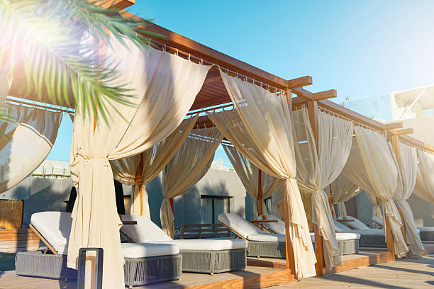 Beach chairs canopy. Luxurious hotel with private pool and beach chairs canopy under umbrellas palm trees and sun loungers for relaxation. Concept summer travel and vacation background.