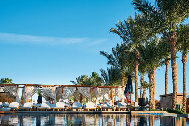 Marsa Alam, Egypt july - 27.2025. A tranquil sunset over a resort swimming pool, with sun loungers and palm trees silhouetted against the colorful sky. Editorial use