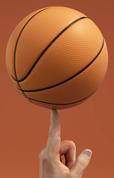 istock Balancing a basketball on a fingertip skillfully in an orange background setting 2226976363