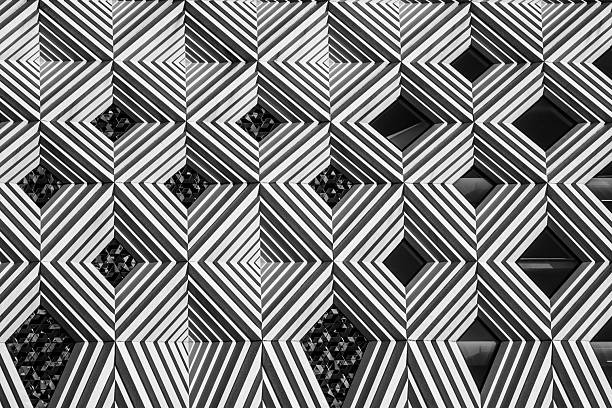 Monotone abstract architectural detail showing a repetitive diamond-shaped pattern on a modern building facade, with dramatic contrast and visual rhythm