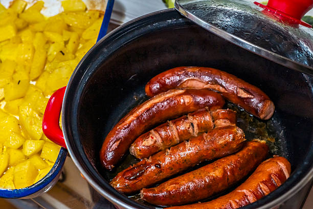 Dinner at home with fried and cooked tomatoes and sausages served in a rustic plates and bowls. Home style eating, serving and cooking.