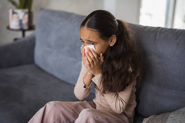 istock Sick elementary age girl blowing her nose on the sofa at home 2226985496