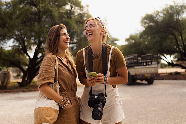 istock Two young women laughing while looking at smartphone on safari trip 2226985536
