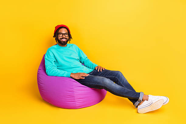 istock Full size profile photo of brunette optimistic guy sit on bag wear cap spectacles pullover jeans isolated on yellow background 2226986269