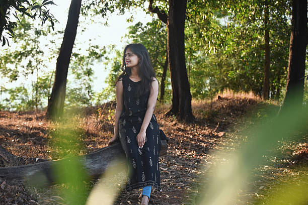 istock Woman Sitting on Log in Forest During Golden Hour 2226988508