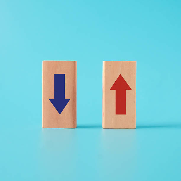 istock Red up arrow in bright side and Blue down arrow on wooden cube block. 2226989906