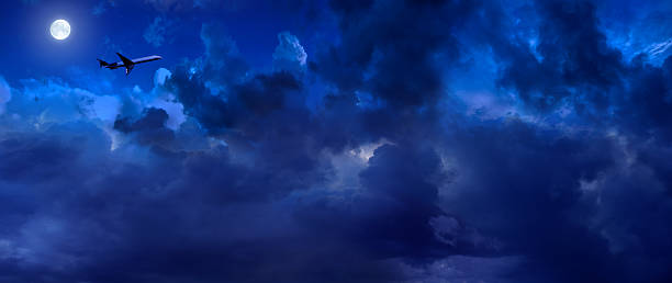 istock Airplane flying over storm clouds in night sky with full moon 2226991380