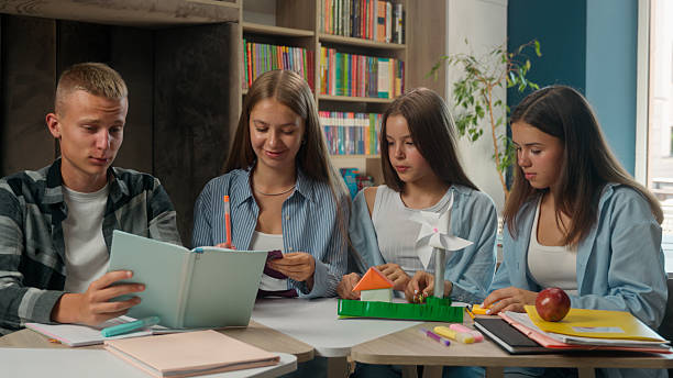 istock Caucasian school classmates pupils teens making paper house task education studying together teenagers girls children kids boy at lesson learning discussing create art learn study talking at desk 2226993081