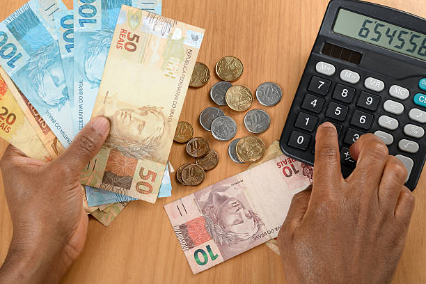 Male hand holding Brazilian real on a graph with a calculator