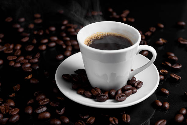 istock A espresso cup filled with dark coffee surrounded by roasted beans on reflective surface. 2226997516