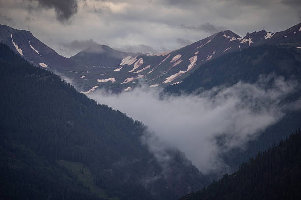 Storm Clouds Spread Through Rugged Snow Covered Mountain Tops at Tree Line, Copy Space