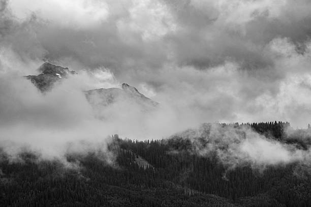 istock Black and White, Storm Clouds Rolling Over Mountain Range at Tree Line, Moody Sky 2227001148