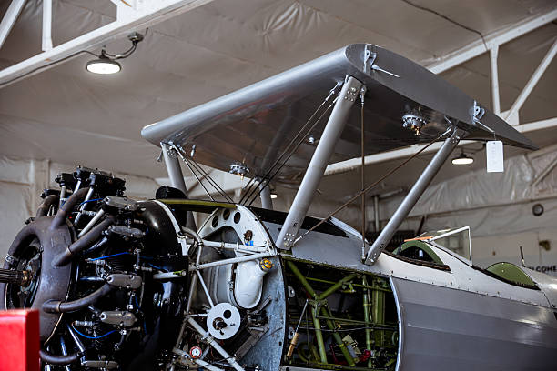 A vintage airplane is being worked on in a hanger for a restoration project. Details of the plane it's self and the project at hand.