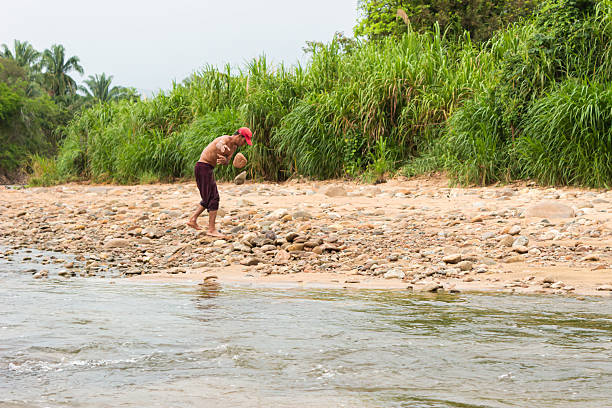 A muscular Colombian man works on sorting stones on the banks of a river in the morning in Neiva, Huila, Colombia. A healthy lifestyle and occupation concept