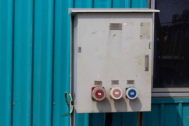 An external electrical box with three colorful outlets is mounted on a vibrant blue corrugated metal wall, showcasing a functional yet industrial aesthetic.