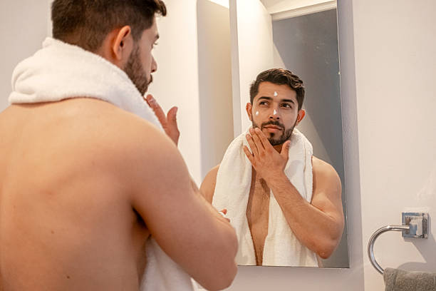 istock young bearded man using facial cream all over his face after showering 2227008328