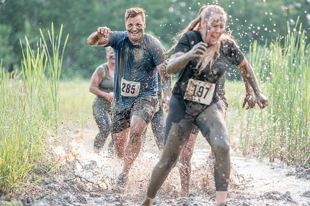 istock Participants Running Through a Muddy Obstacle Course Race Outdoors 2227010891