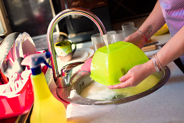 Middle aged woman washing dishes in the kitchen at home.