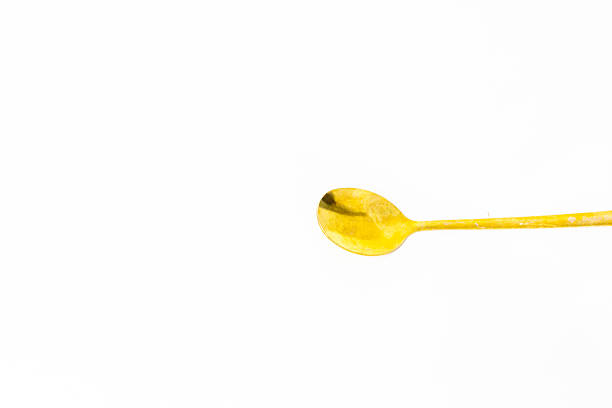 Elegant golden teaspoon on white backdrop ideal for culinary visuals, lifestyle content or showcasing fine dining elegance. A pristine aesthetic emphasizing quality and minimalist design gold