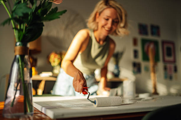 istock Female artist priming canvas with paint roller in art studio 2227019700
