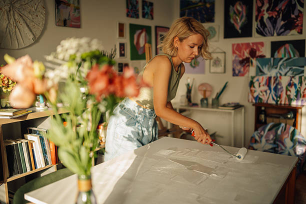 istock Female artist priming canvas in sunny art studio 2227019720