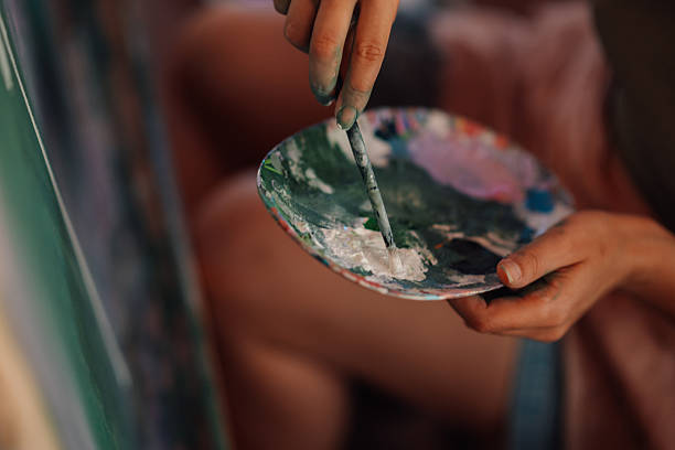 istock Artist picking up white paint from palette while painting 2227019954