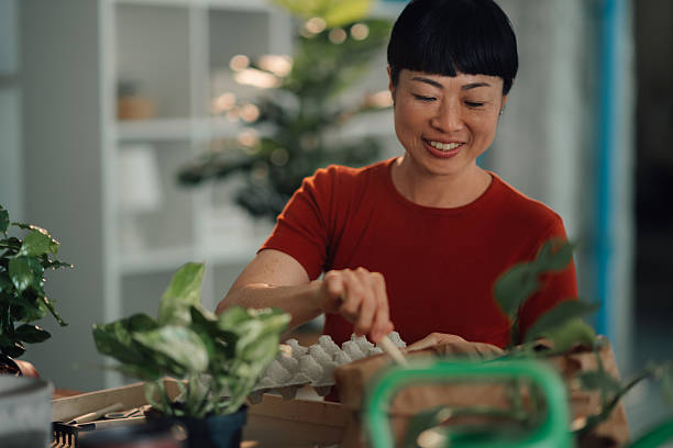 istock Woman repotting plants at home using recycled egg carton 2227021154
