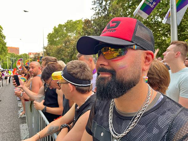 Madrid, Spain - July 5, 2025: Bearded man with rainbow makeup on his face, attending the Madrid Gay Pride parade, known as MADO, in Paseo del Prado, Madrid, Spain, enjoying the festive atmosphere. In 2025, Spain celebrated 20 years of equal marriage, becoming the third country, after the Netherlands and Belgium, to have the law come into effect on July 3, 2005.