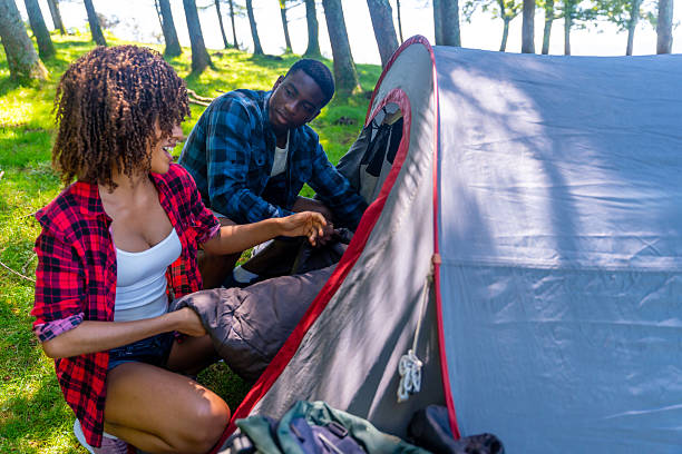 istock Happy couple setting up tent in forest during camping trip 2227026222